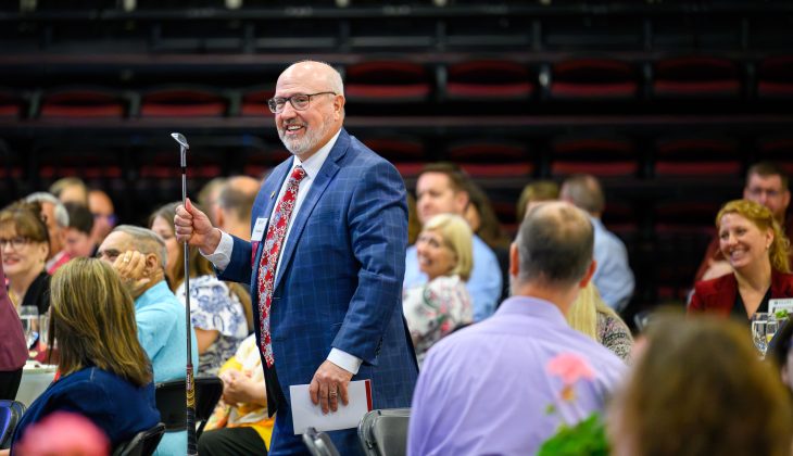 Robert Moorman holds a golf club gifted by Haya Ajjan during the 2026 Faculty-Staff Awards at Alumni Gym on May 12, 2026. (Photo by Grant Halverson/Elon University)