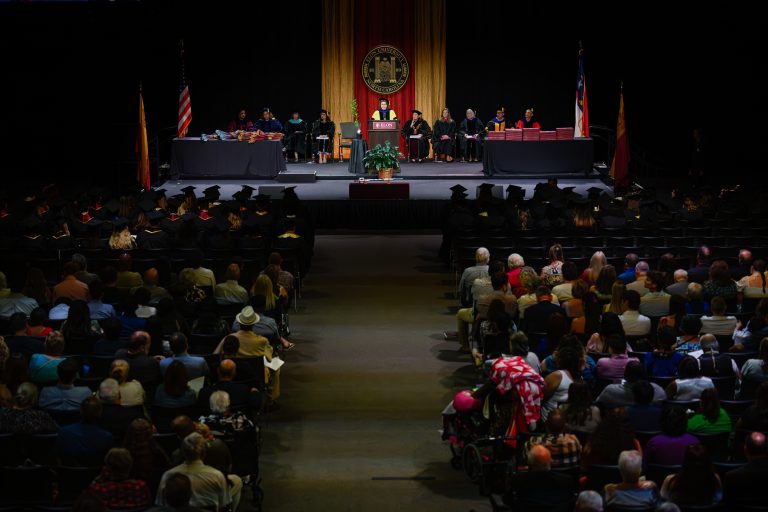 A wide view of Elon University’s Graduate Commencement ceremony shows graduates, faculty and audience members gathered in Alumni Gym.