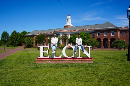 Bernardo Vargas-Lopez '26, a sport management major from Austin, Texas, and Juan Daniel Chiriboga '26 on the Elon University sign in front of the Admissions building