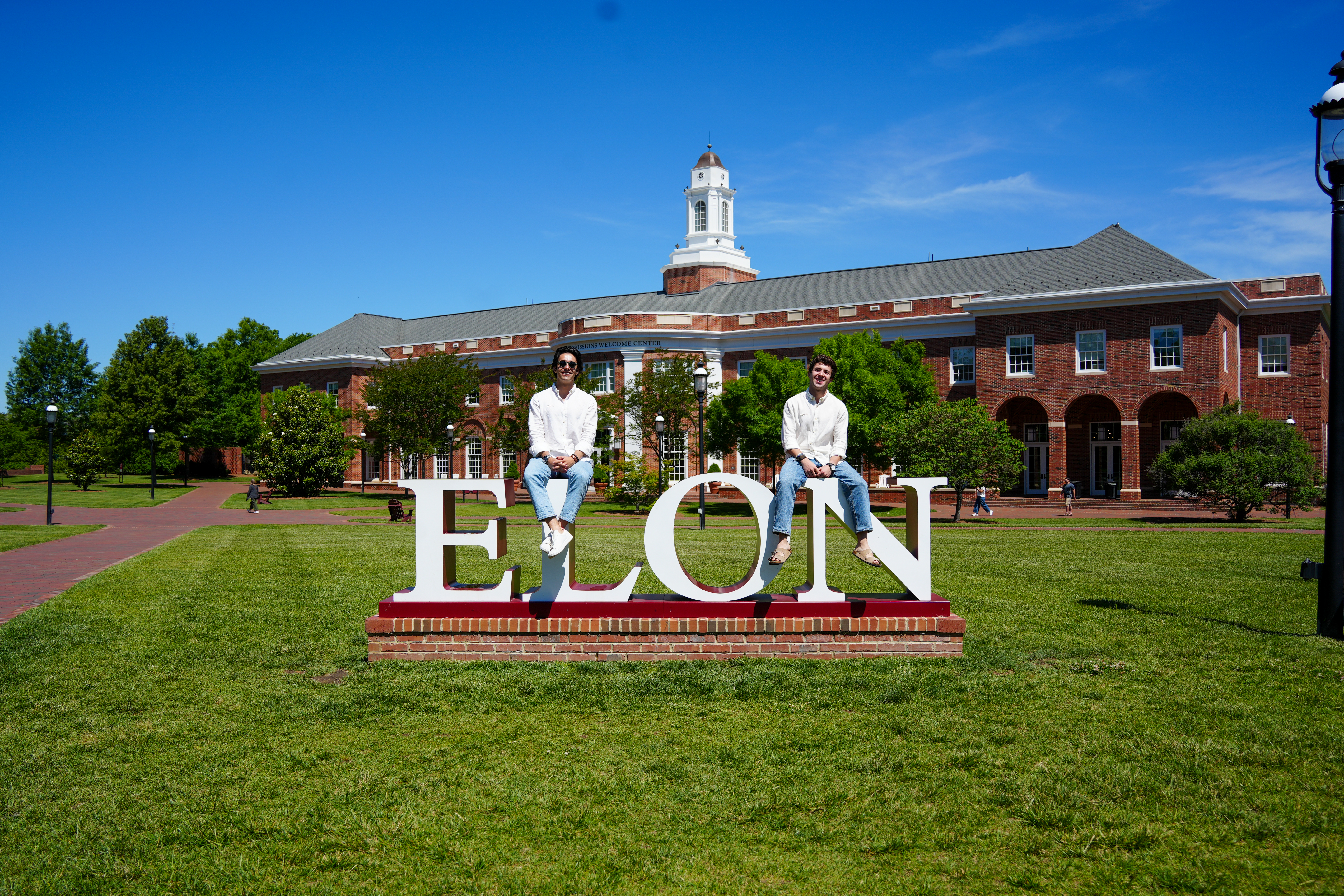 Bernardo Vargas-Lopez '26, a sport management major from Austin, Texas, and Juan Daniel Chiriboga '26 on the Elon University sign in front of the Admissions building