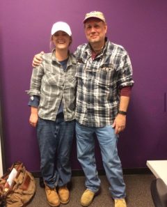 Kathleen Hart dressed up as Michael Strickland. They are wearing a flannel shirt with jeans and boots.