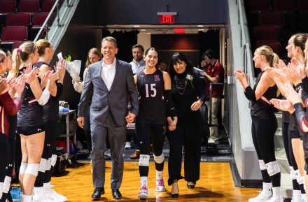 Simrin Carlsen G’26 poses with two family members on the court inside Schar Center.