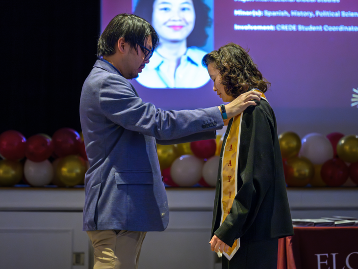 Student receiving stole from George Dou, assistant director of the Center for Race, Ethnicity and Diversity Education, during the 2026 "Light the Way" celebration.