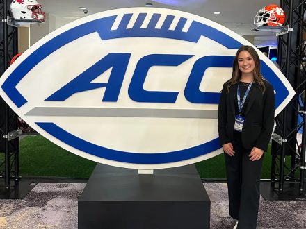 Lucy McAfee with ACC logo sign