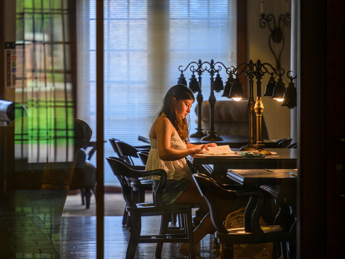 A student studies at a table inside one of Elon University’s campus academic spaces.