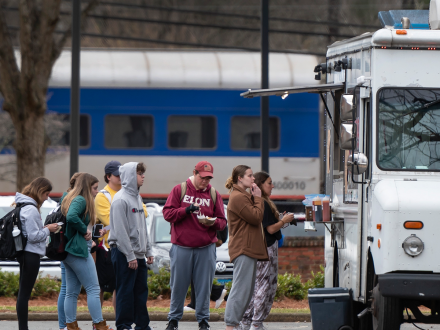 Students line up at a campus food truck, waiting to order and pick up meals between classes.