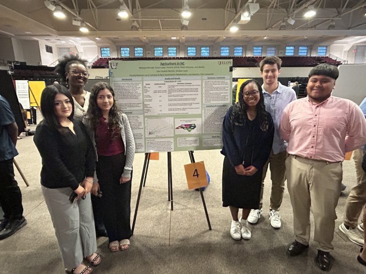 Six people standing in front of a poster about agriculture in North Carolina