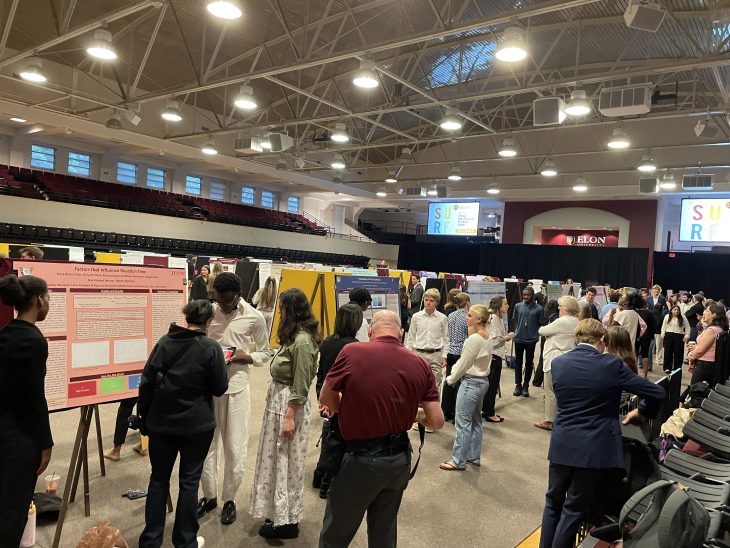 Students from each of the five groups presenting their research to poster visitors