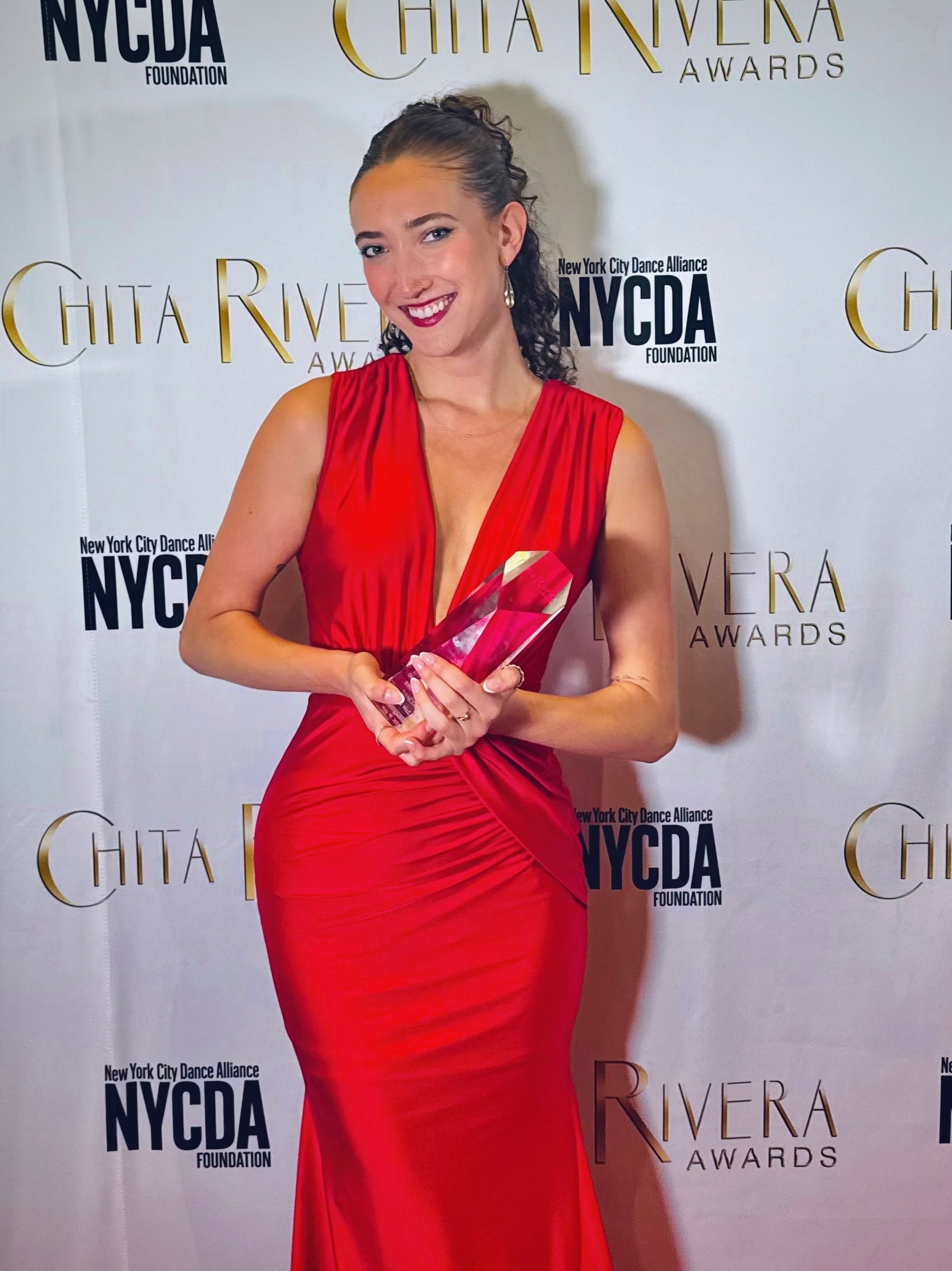 Helena Padial wearing a red dress and standing with her trophy at the Chita Rivera Awards on May 18.