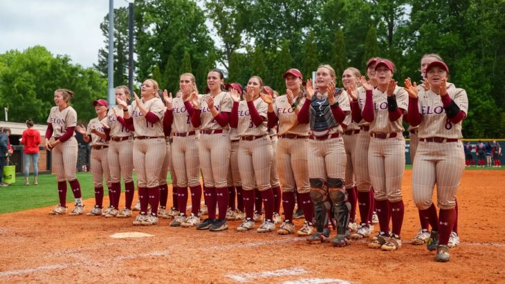 Elon University softball players stand in a line and cheer