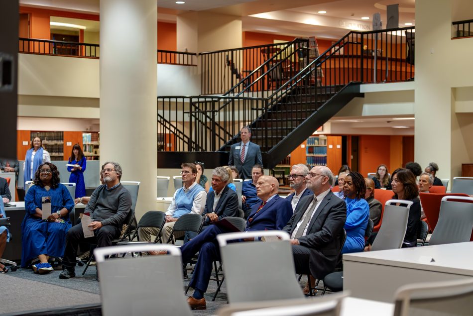 A group of people seated in a large library common area.