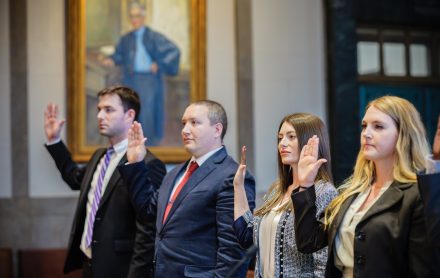 Two men and two women raise their right hands as they swear an oath in a courtroom.