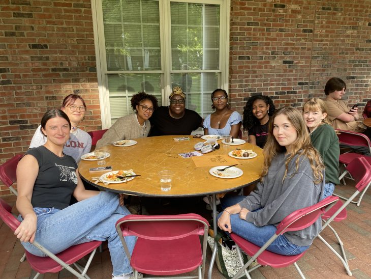 A group of students pose for a photo while seated at circular table