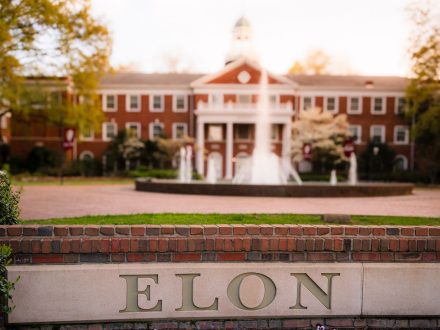 A photo of a campus wall with "���ϲ�����" inscribed in the foreground of an image that also shows Alamance Building and Fonville Fountain in the background.