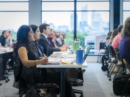 A group of law students seated at long desks in a classroom overlooking the Charlotte skyline.