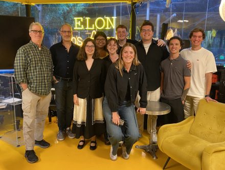 A group of people pose together, with the illuminated “Elon Los Angeles” sign in the background.