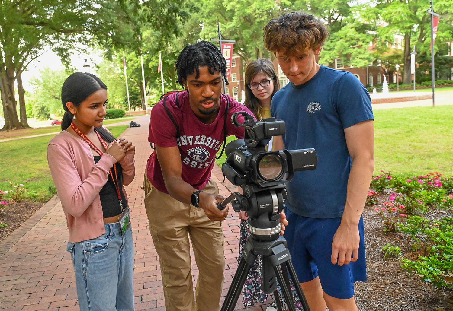 Three EJP students and mentor Blair Mitchell handle a camera on Elon's campus