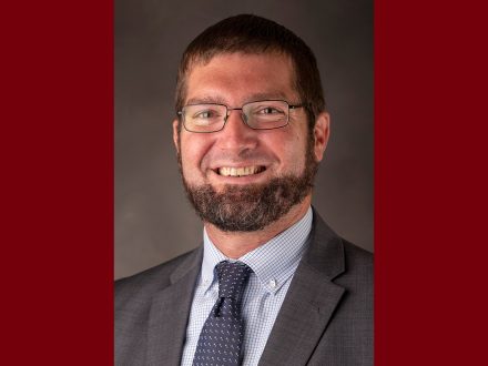 headshot of Evan Small on maroon background