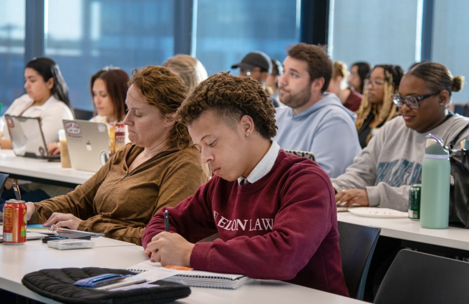 A group of law students taking notes during a classroom lecture.