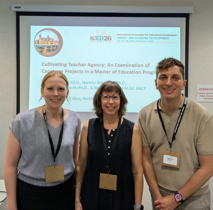 Three people pose for a photo in front a presentation projector screen