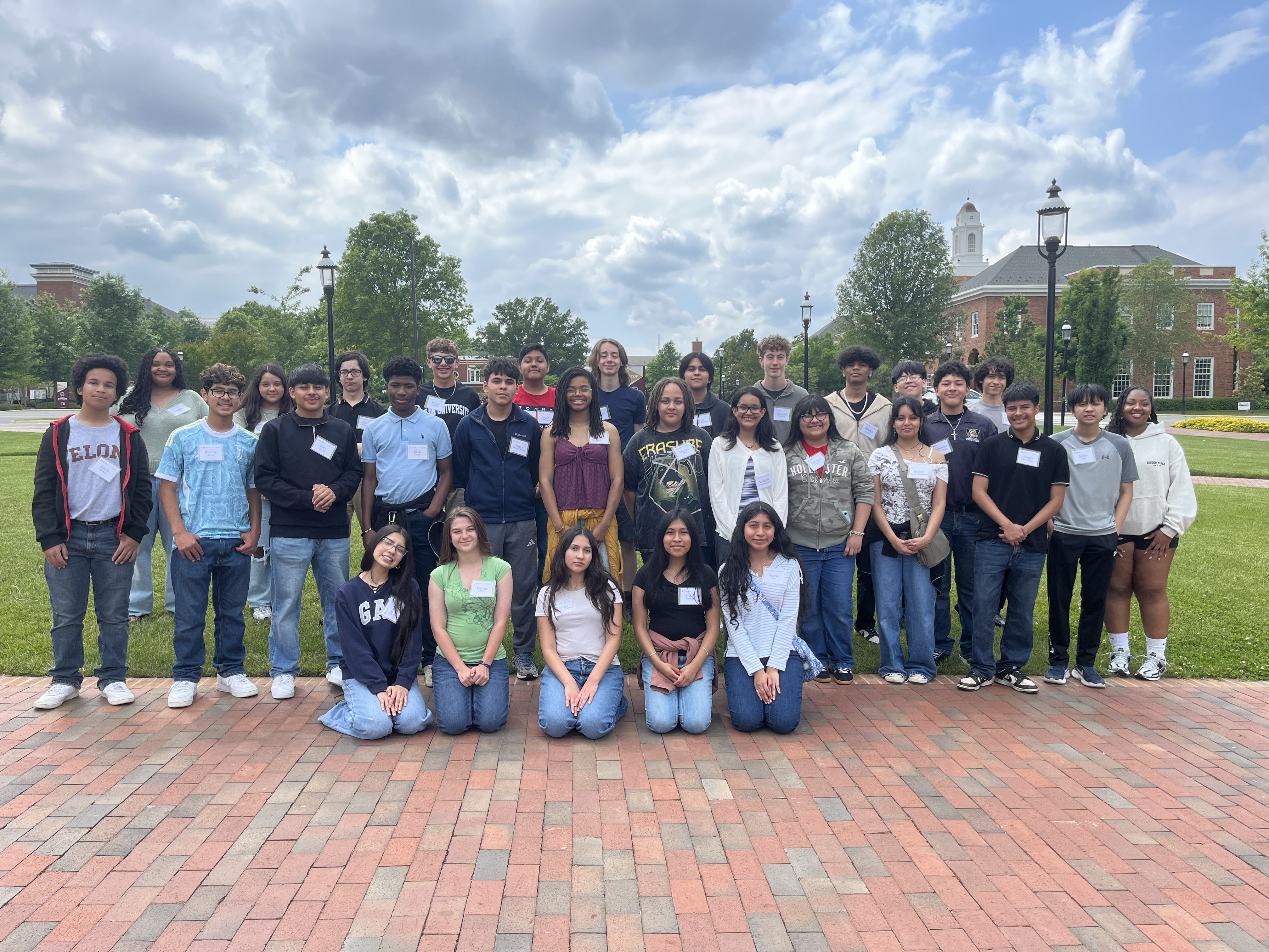 A group of young people pose for a photo on a brick walkway