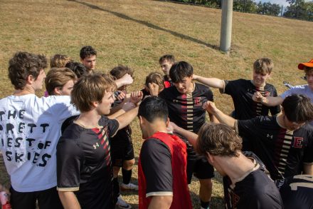 A group of soccer players put their hands togehter in a huddle