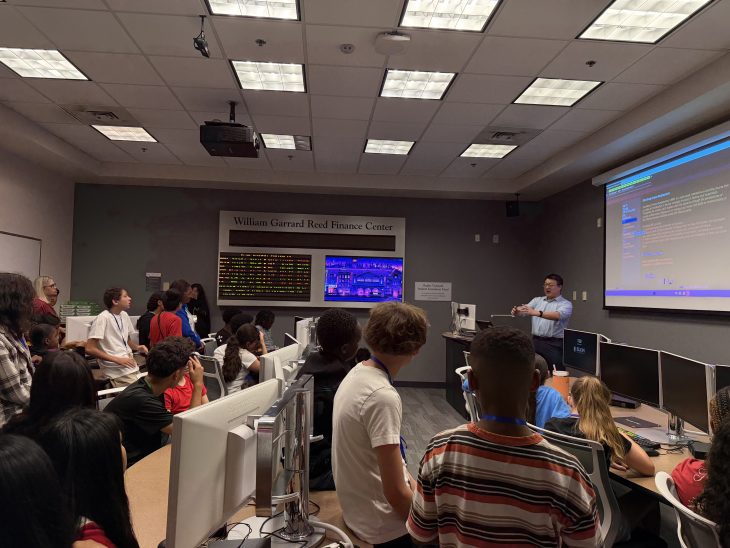 Students watch a faculty member demonstrate computer programming in the William Garrard Reed Finance Center.