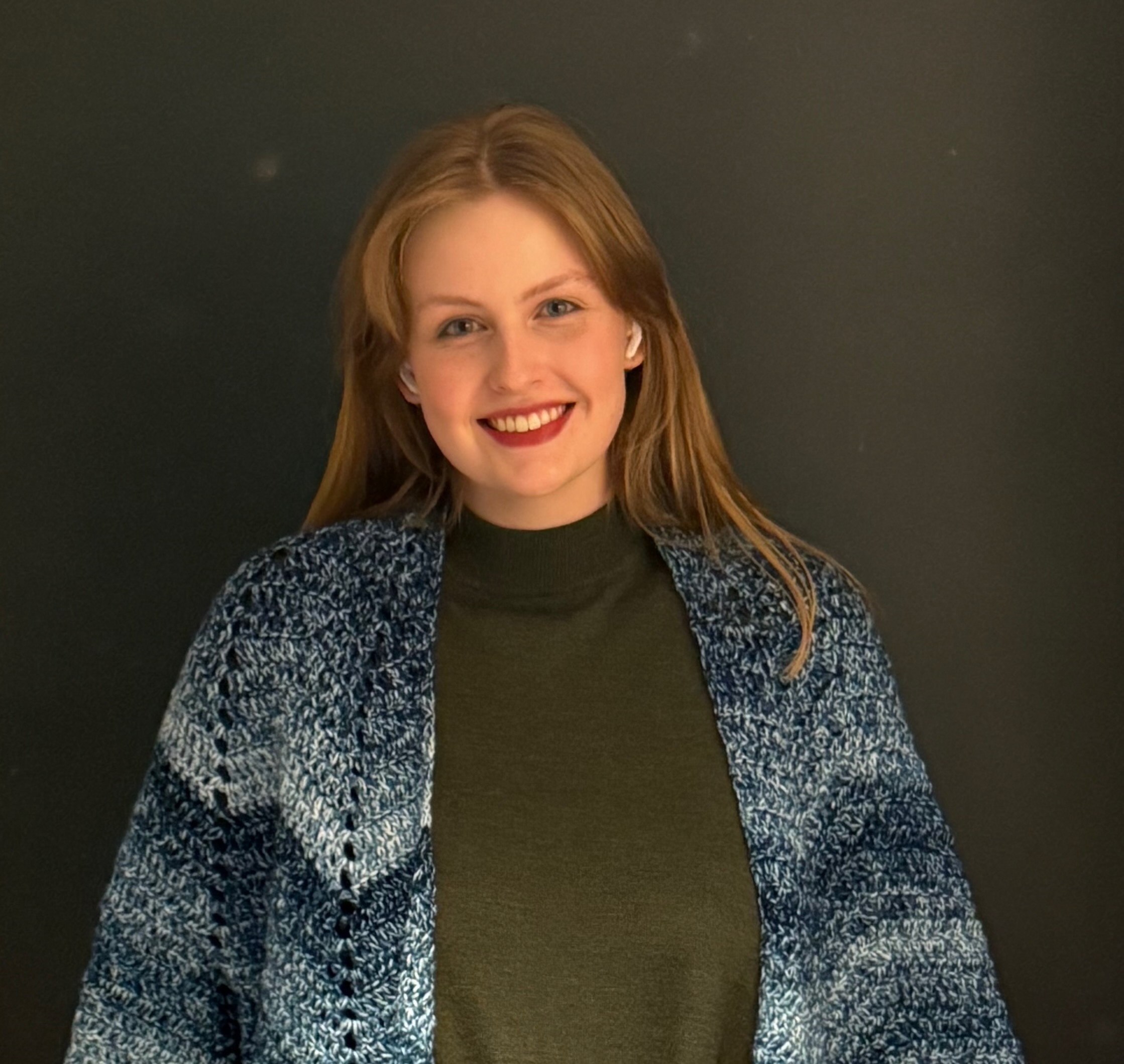 Headshot of a woman in a green shirt and blue cardigan sweater