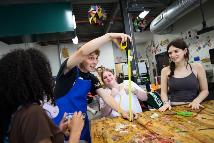 Students collaborate in Elon University’s Maker Hub, measuring and testing a spaghetti tower design as part of a hands-on engineering and problem-solving activity.