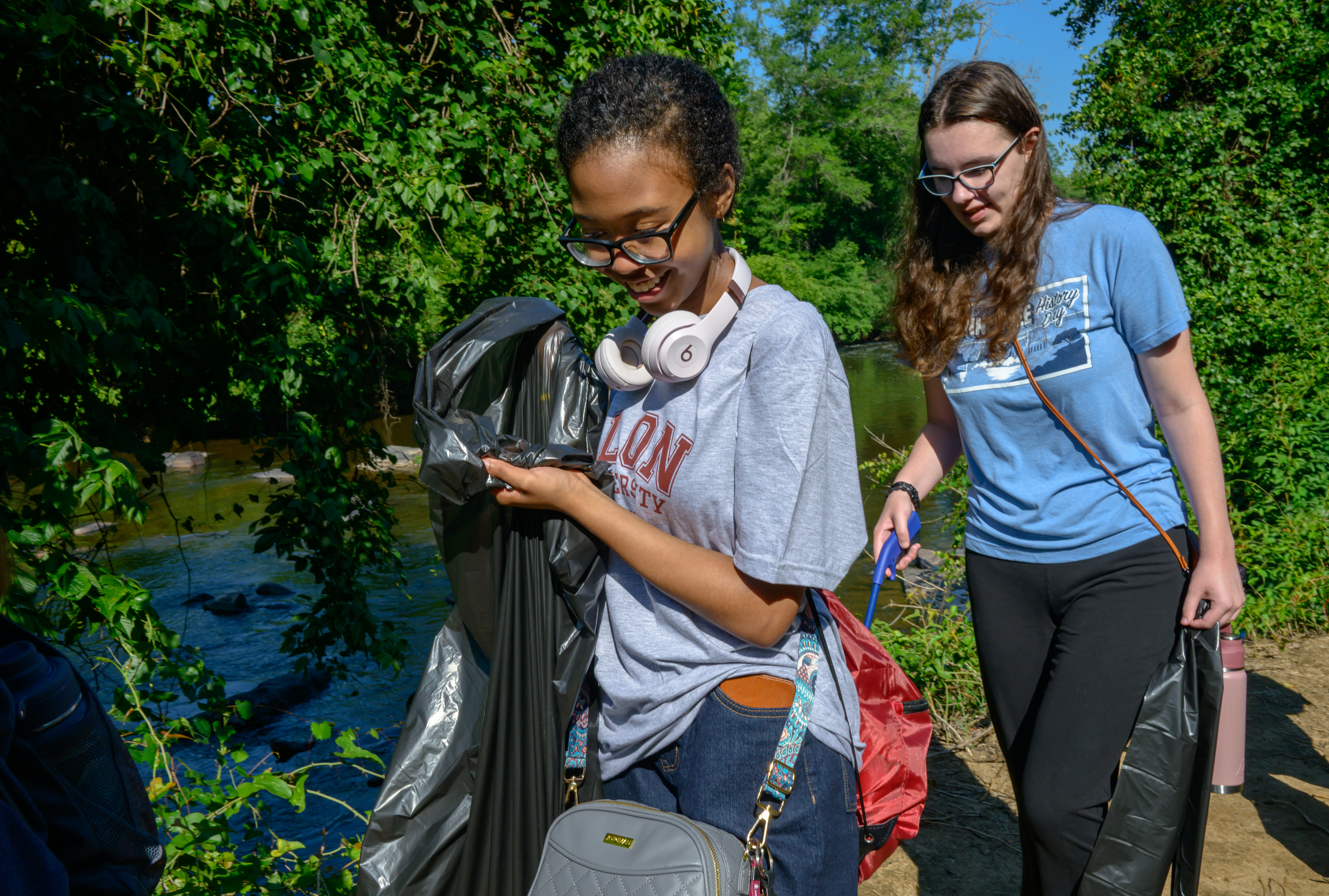 Two 51������ students collect litter along a river during community service project, helping clean local trails and waterways