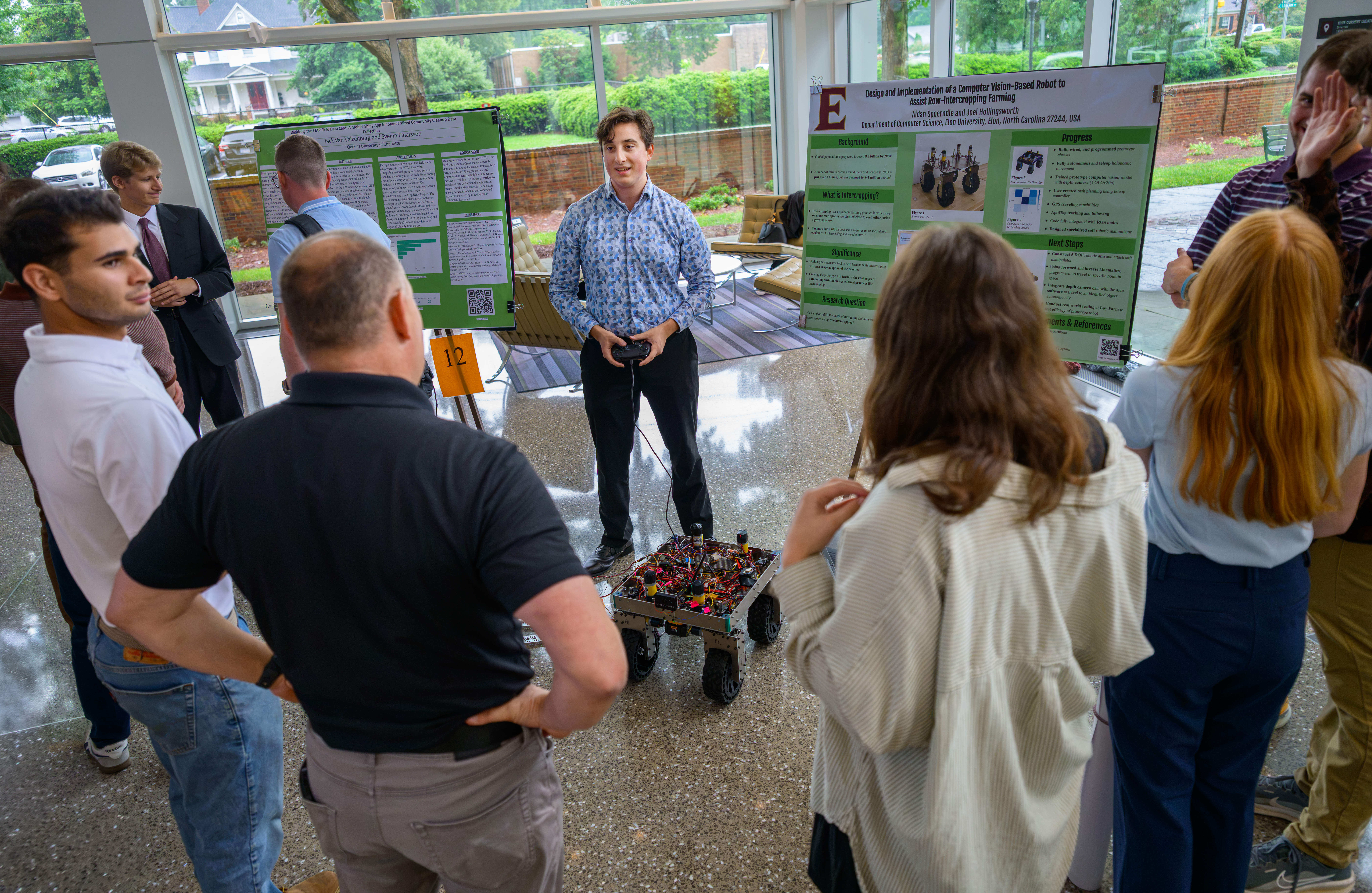 An 51������ student demonstrates a computer vision-based agricultural robot to attendees during the Summer Undergraduate Research Experience (SURE) poster presentations.