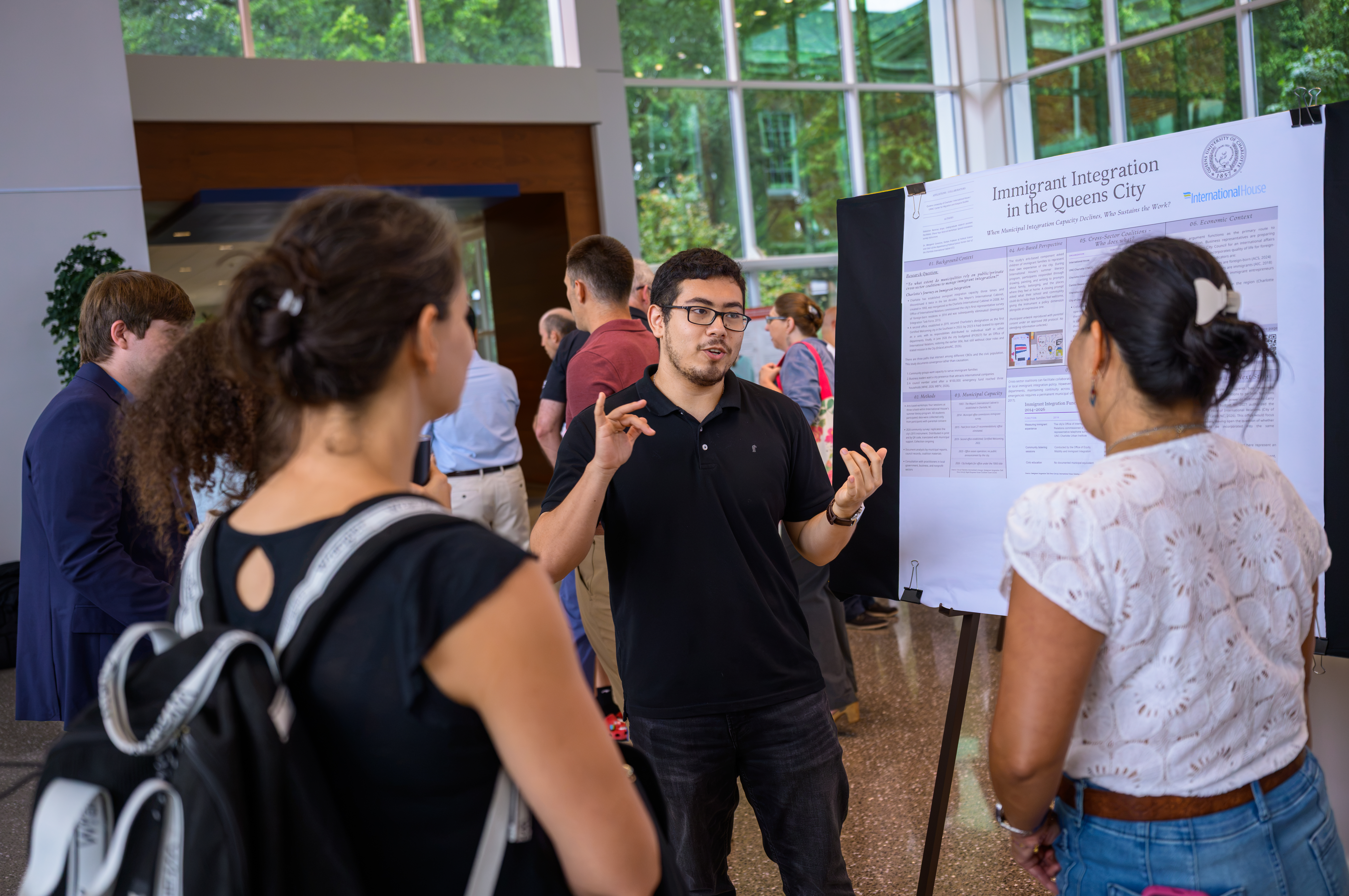 A student presents research on immigrant integration in Charlotte during a poster session at the Summer Undergraduate Research Experience.
