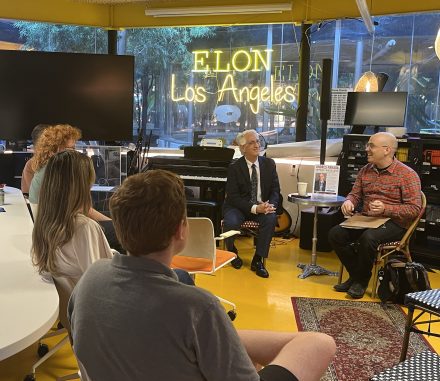 A speaker and moderator lead a discussion with students inside Elon Los Angeles, where participants are seated in a collaborative workspace beneath the illuminated “Elon Los Angeles” sign.