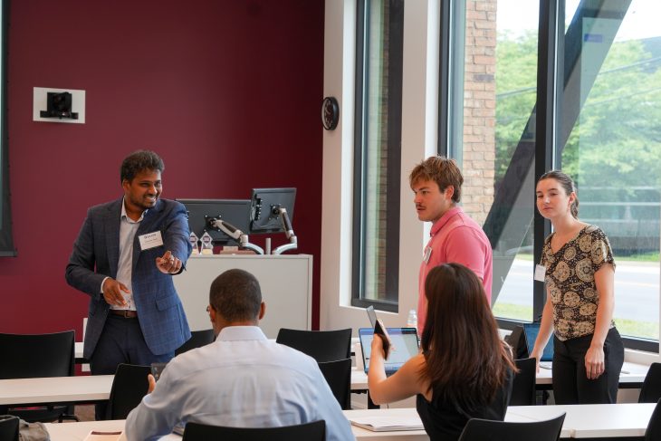 Vinakaya Gude speaks with participants working at tables