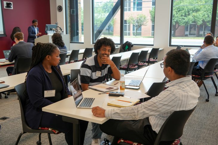 Participants sit around a table discussing ideas and reviewing information during the Charlotte Decision Challenge.