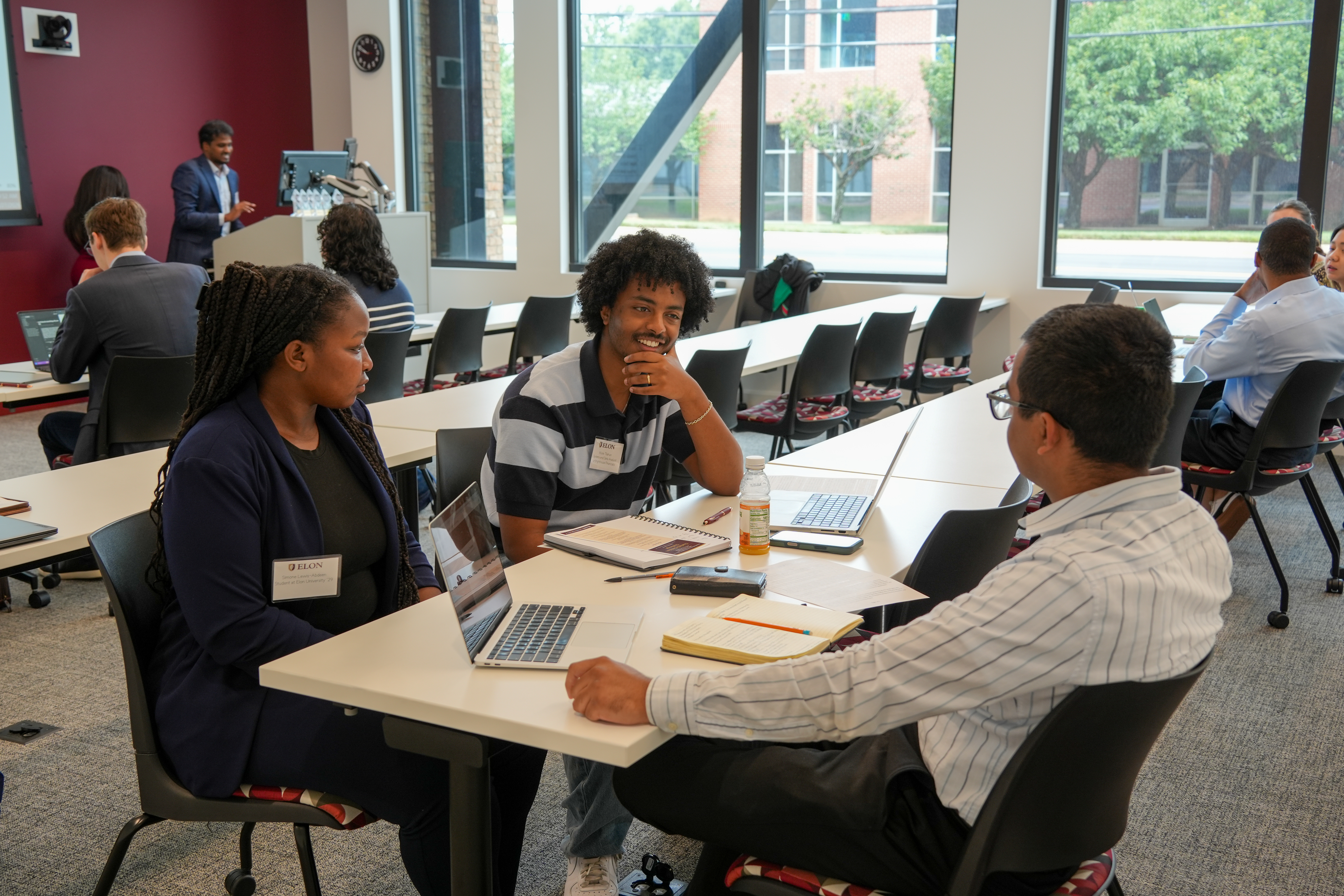 Participants sit around a table discussing ideas and reviewing information during the Charlotte Decision Challenge.