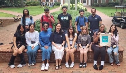 A group of people pose for a photo sitting on a brick wall