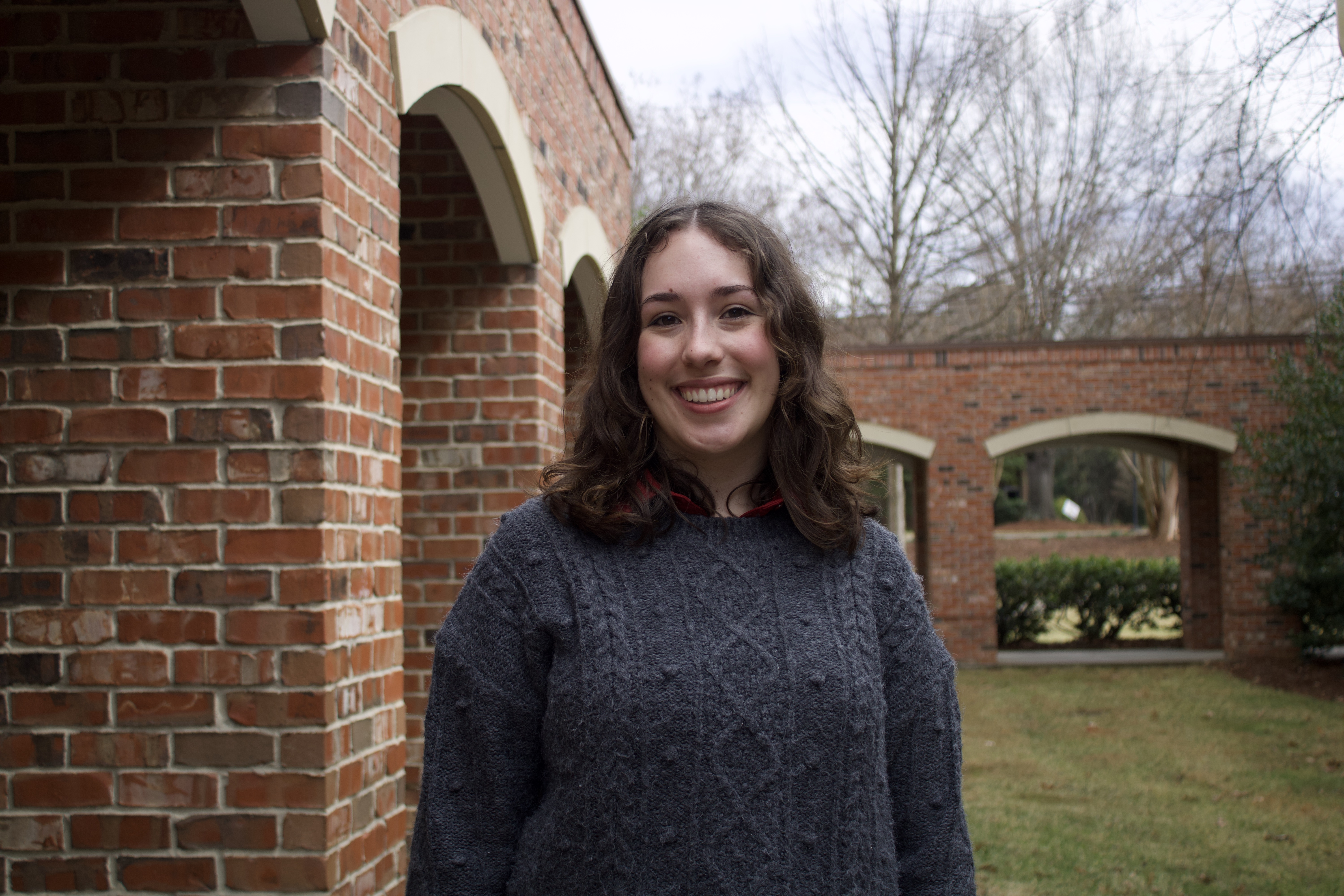 Portrait of a woman in a gray sweater with brick archways behind her