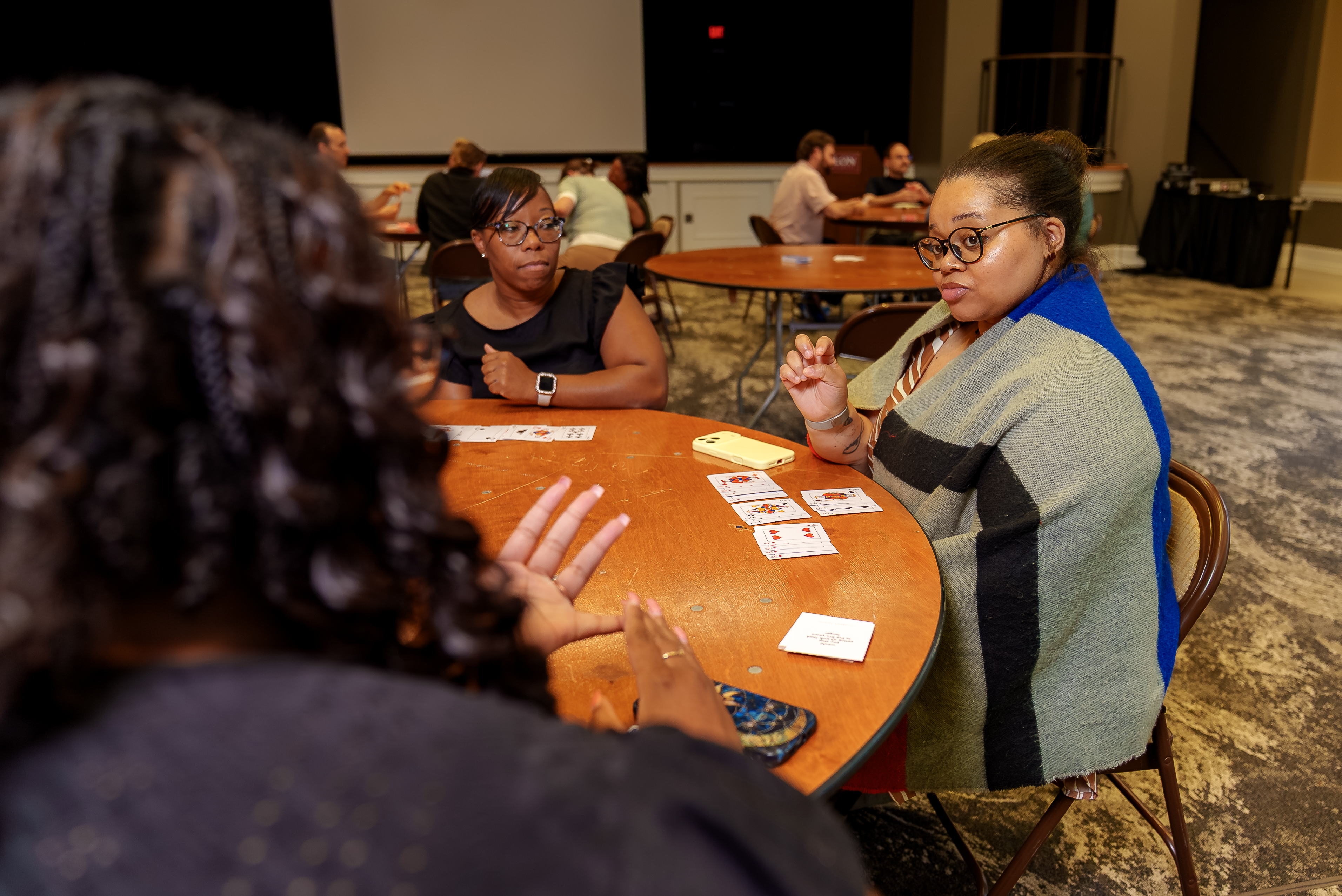 People sit around a table playing a card game