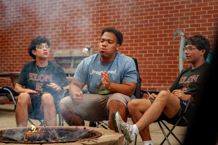 Three Phoenix Summer students sitting around a fire making s'mores