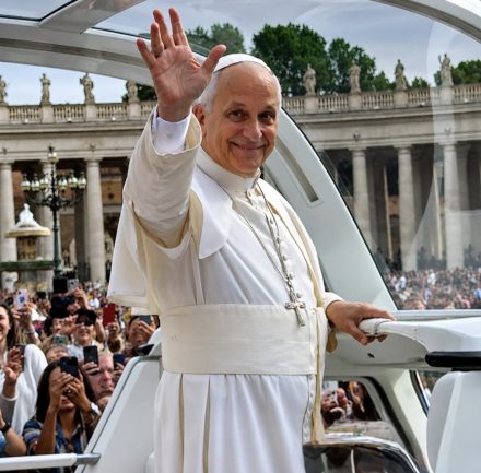 The pope waves from a vehicle as a crowd gathers behind him in St. Peter鈥檚 Square. Ornate colonnades and statues line the background of the Vatican setting.