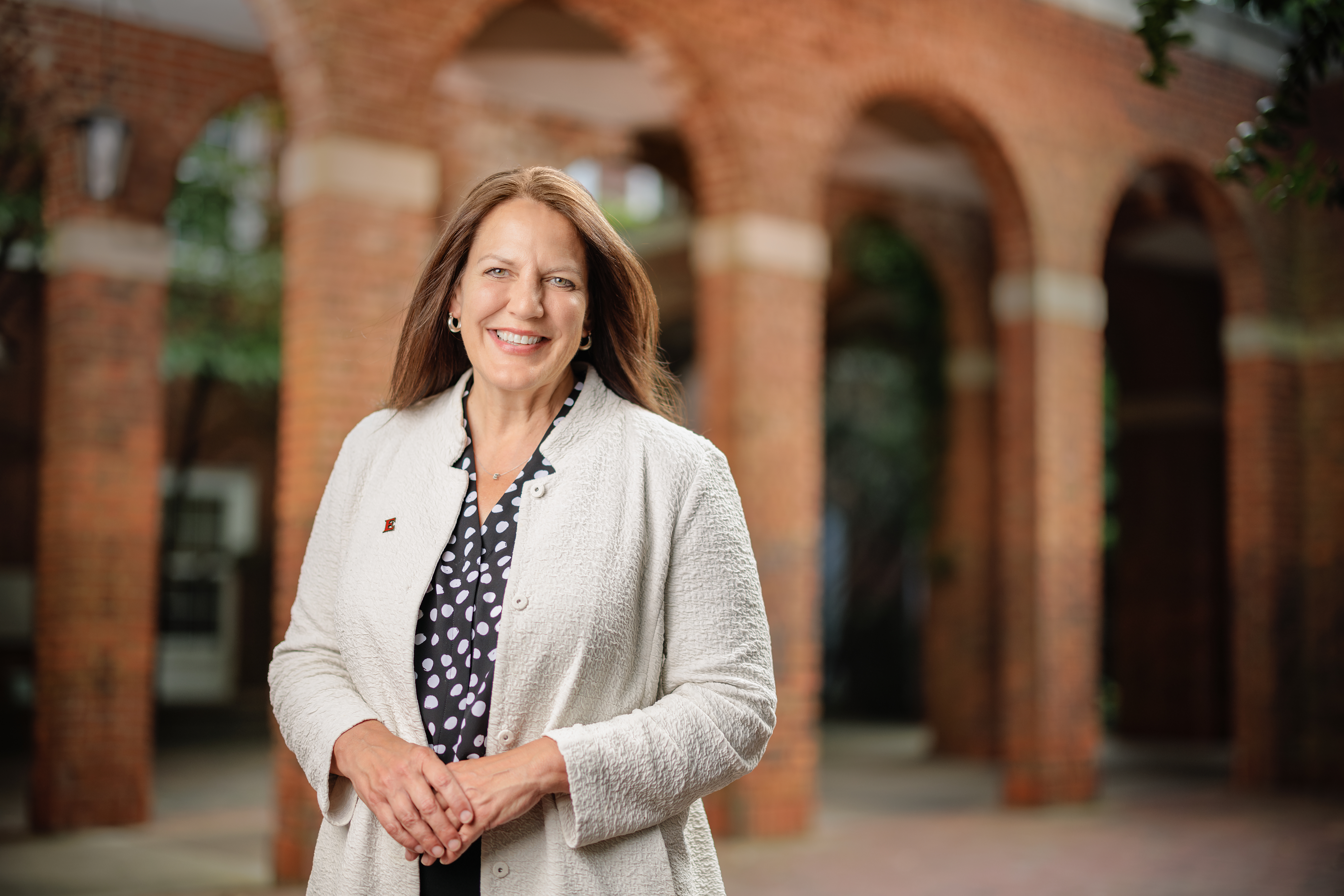 Elon University President Connie Ledoux Book smiles while standing beneath the brick arches on Elon University’s campus.