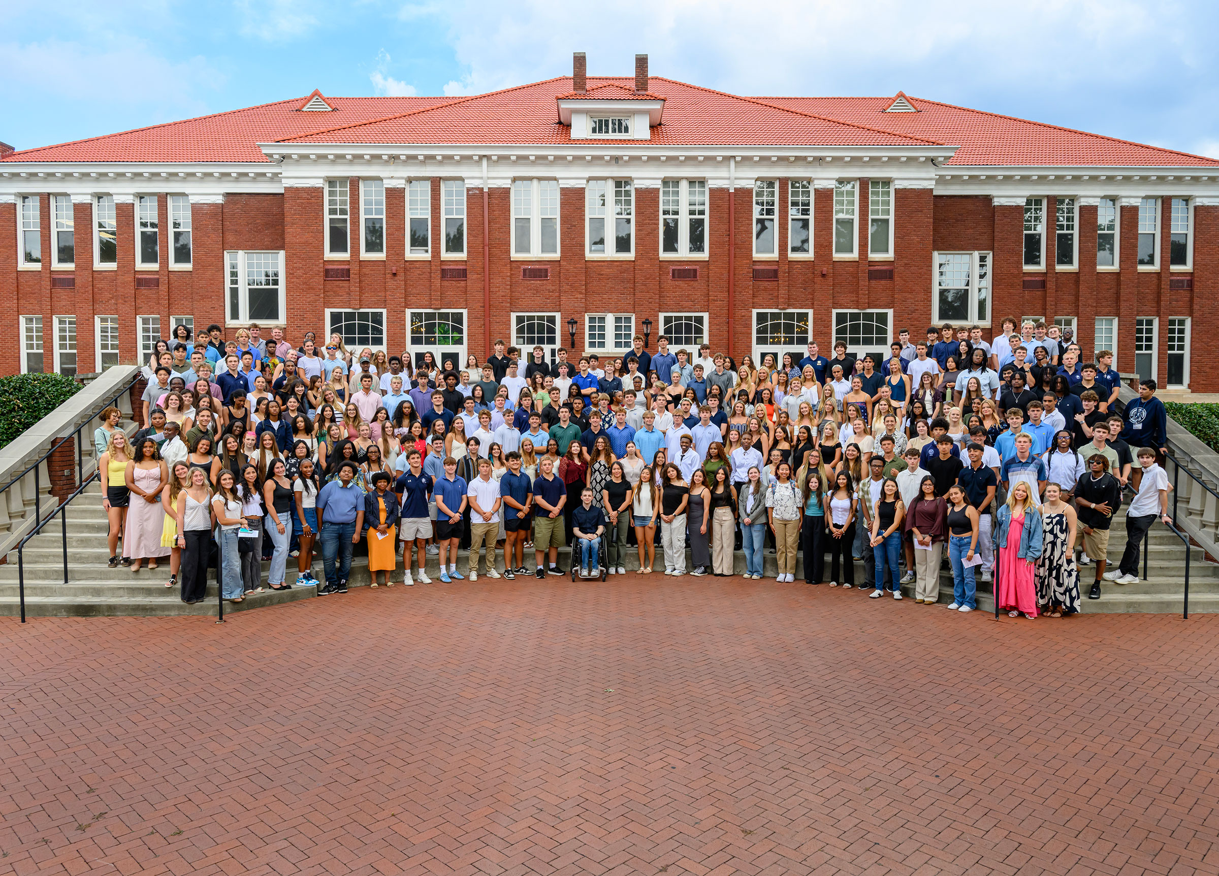 More than 300 Queens University students gather at the steps of Hall Brown Terrace in front of a red brick building known as Queens Hall.