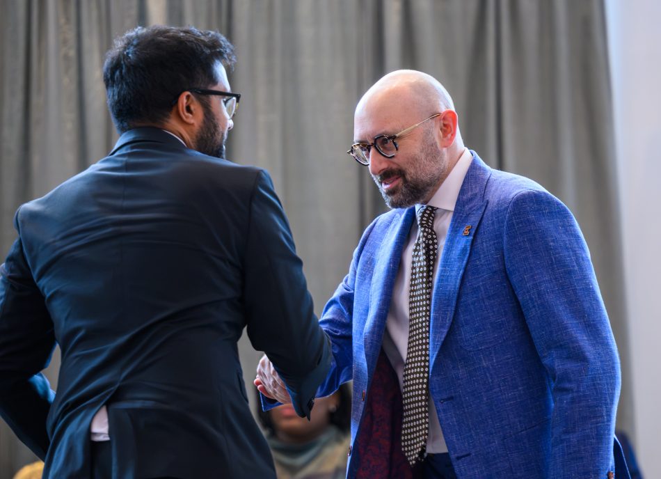 Two people shaking hands on a stage. They are making eye contact and smiling.