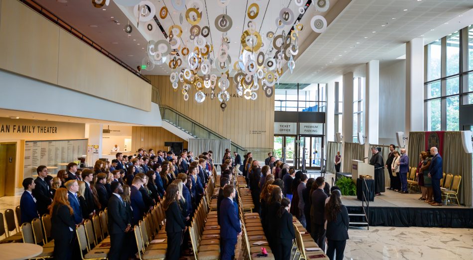 A large group of students standing in a large venue for Convocation