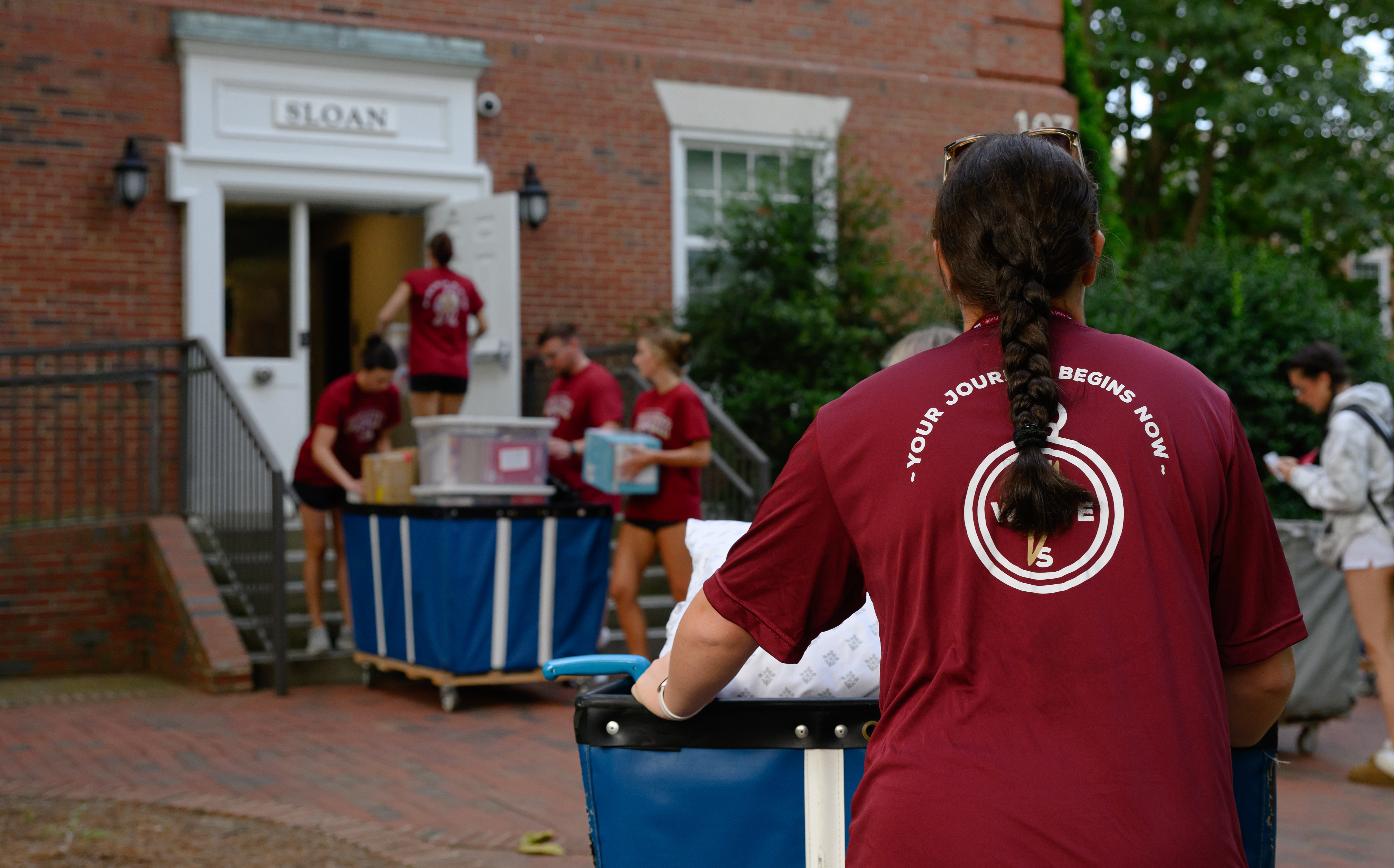 Orientation leaders push carts of student belongings into Sloan residence hall during Elon University Move-In Day.