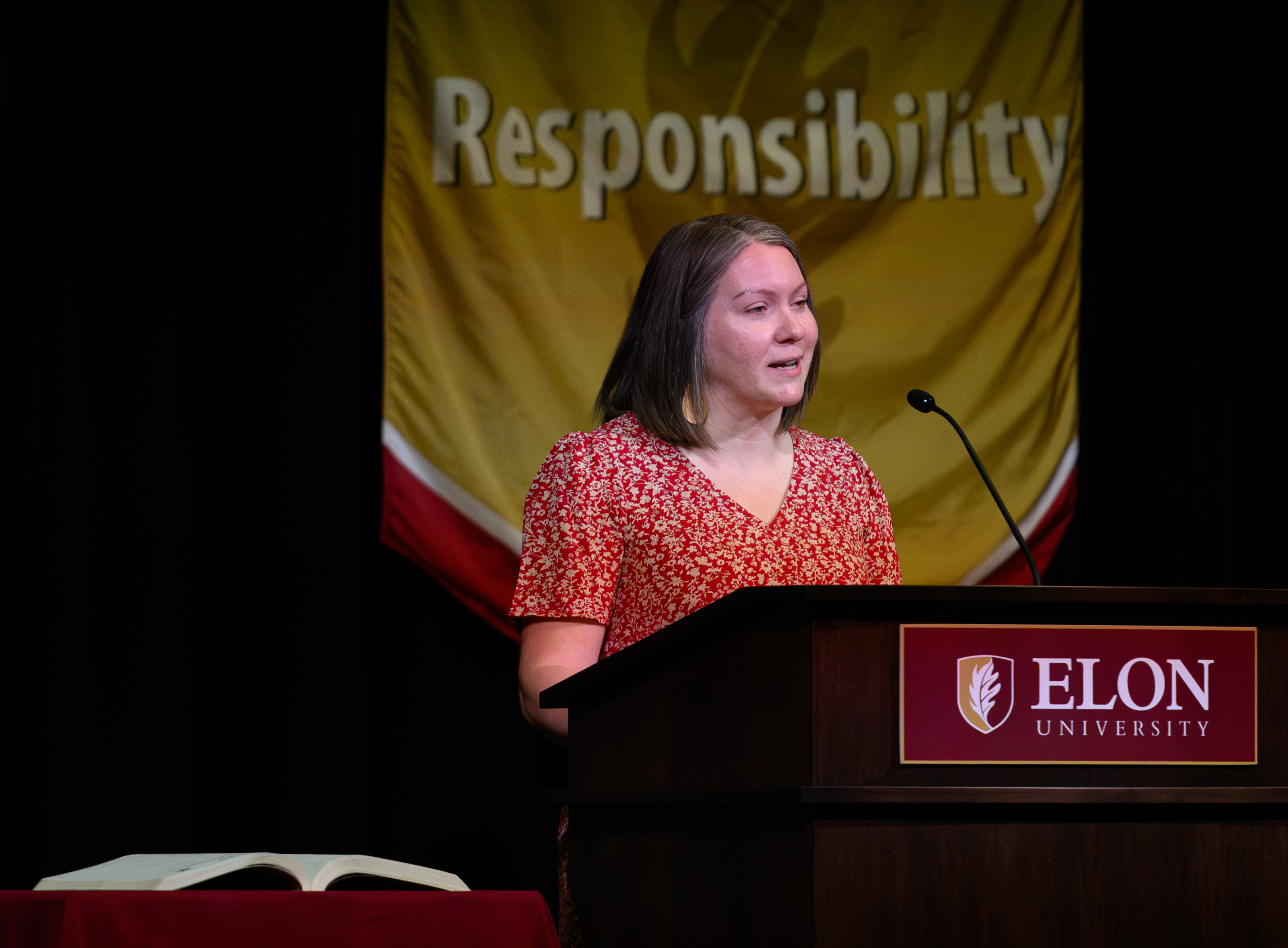 A woman speaks at an ������Ƶ podium with a large “Responsibility” banner behind her during the Call to Honor ceremony.