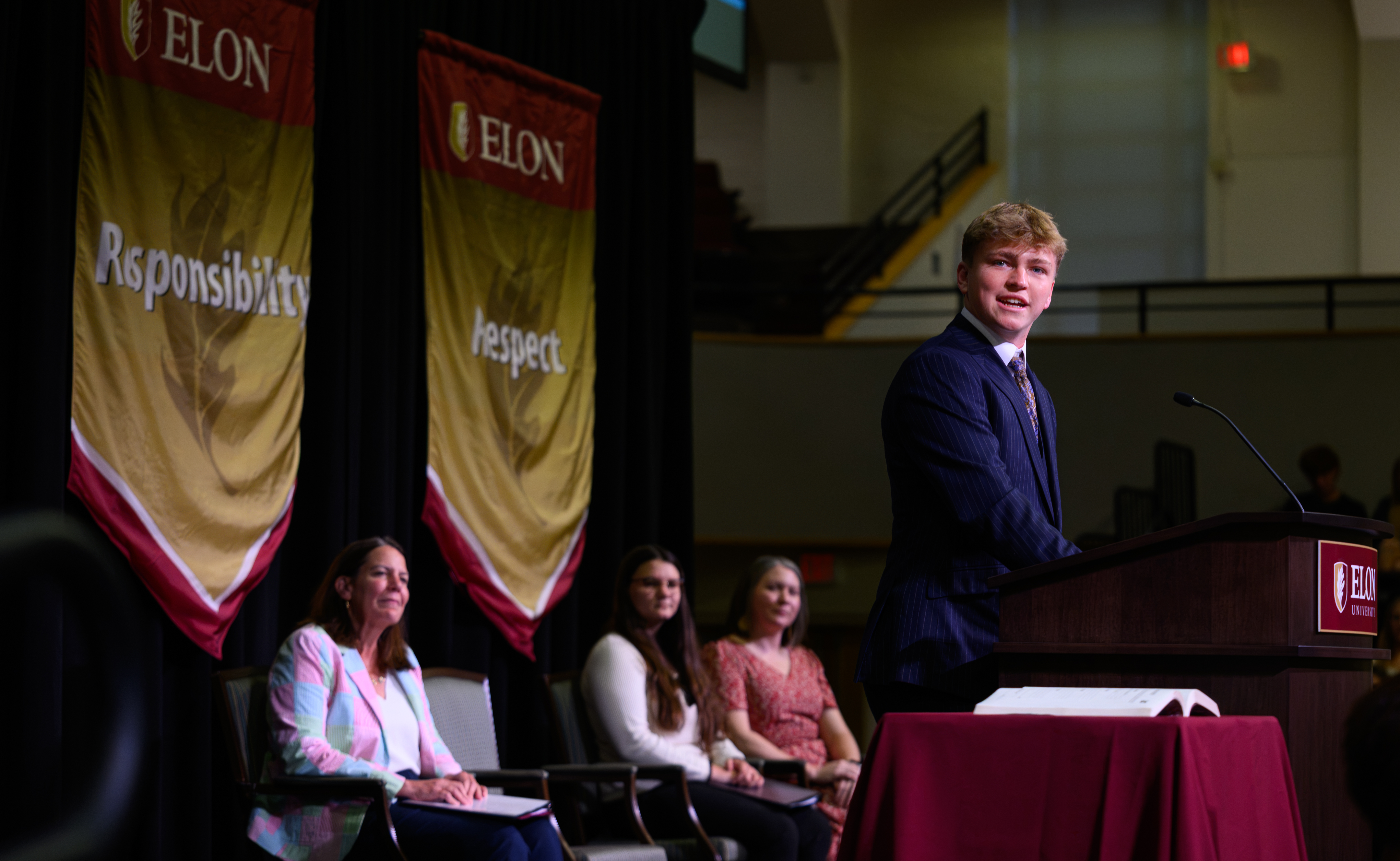 A student speaks at a podium during ������Ƶ’s Call to Honor ceremony as university leaders and students sit behind him onstage.