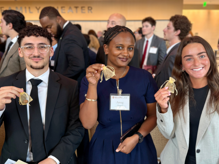 Three people hold small gold bags with acorns inside.