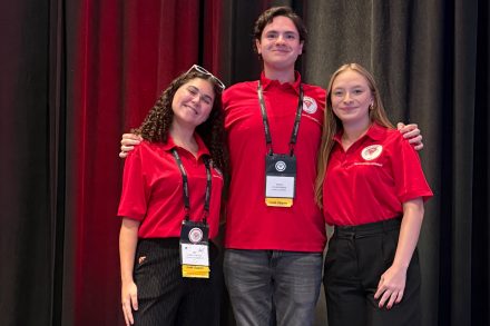 Izzy Butler, Dylan Rogers and Kaitlyn Niestoeckel stand together in matching red Elon Beta Alpha Psi shirts at the organization’s annual meeting in Baltimore.